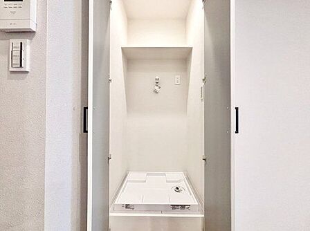 生活感が出ないよう、洗濯機を扉の中へ収納しました。収納棚もあって、効率よく家事をこなせます。