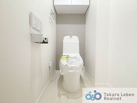 白を基調とした清潔感のあるトイレ。上部に収納もついておりますので、とても便利です。