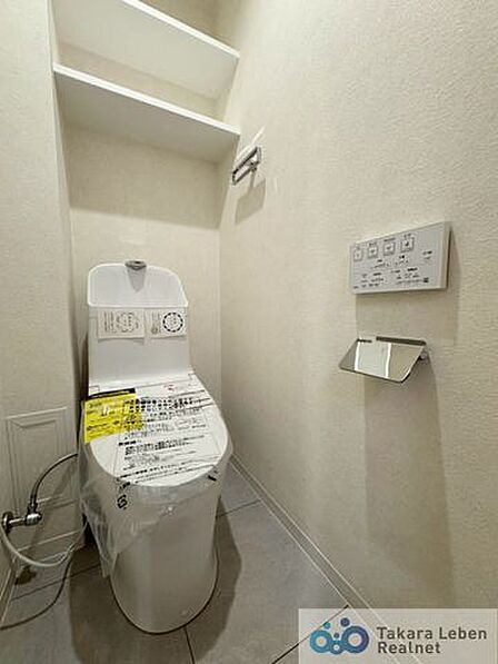 ウォシュレット機能付きのトイレは壁掛けリモコンの上位グレードを採用。便座がスッキリした印象となり、限られた空間を広く見せる効果があります。