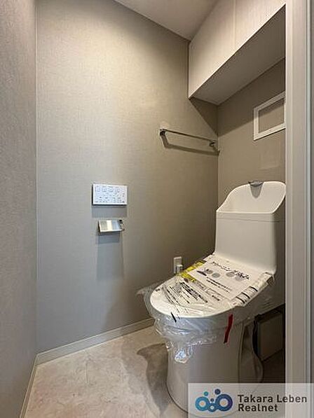 ウォシュレット機能付きのトイレは壁掛けリモコンの上位グレードを採用。便座がスッキリした印象となり、限られた空間を広く見せる効果があります。