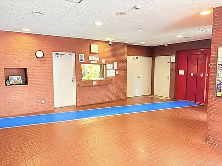 レンガ調の壁面が重厚で趣のある佇まいを感じさせ、日常に安心感と温もりを添えてくれる共用空間です。