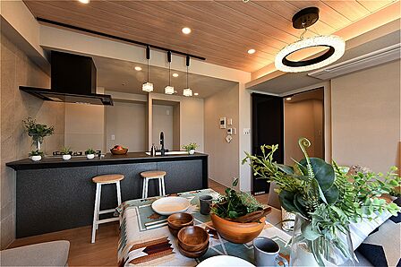 木目調の天井とダークカラーのキッチンが調和した空間。キッチン前にダイニングテーブルを配置すると、配膳や片付けがスムーズに。調理や片付けをしながらの会話も弾みます。