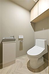 トイレには手洗いカウンターを設置。使用後すぐに手が洗え衛生的です。背面の吊戸棚にトイレットペーパーや掃除用品などを収納できます。