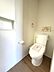 トイレ：清潔感のある壁紙と木目調の床が調和したトイレ空間。収納棚も備え付けられており、すっきりとした印象です。快適な毎日をサポートします。