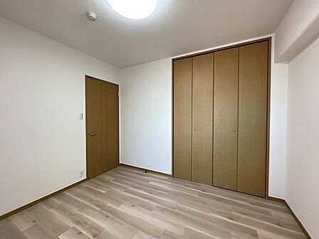 明るい木目調のフローリングが特徴的な洋室です。クローゼットも備え付けられており、収納も充実しています。