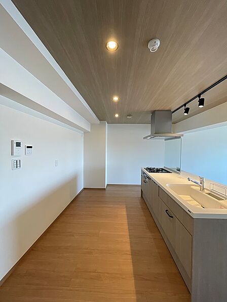 木目調の天井とダウンライトが、空間に温かみと上質感を演出するキッチンです。広々としたカウンターは作業効率を高め、料理の時間をより快適にします。