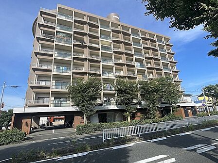 青空が映える外観のマンションです。エントランスには駐車場があり、お車でのアクセスも良好です。ぜひ一度ご内覧ください。