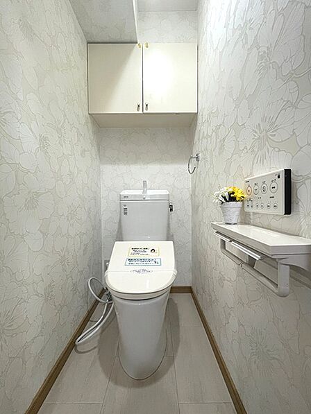 清潔感あふれるトイレは、爽やかな花柄の壁紙が印象的。吊戸棚や飾り棚も設置され、収納力と使いやすさを両立しました。毎日を快適に過ごせます。