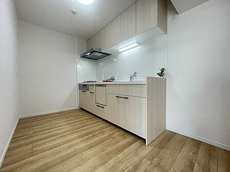 明るい木目調のフロアと清潔感のある壁が調和したキッチン。調理スペースも確保されており、お料理の時間を快適に過ごせます。