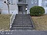 エントランス：丁寧に手入れされた植栽が優しく出迎えるエントランスは、住まう人の品格を感じさせます。手すり付きの階段が設けられた安心の設計で、毎日を健やかに支える細やかな配慮が随所に散りばめられています