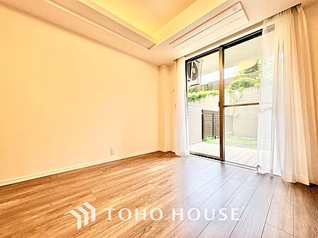 大きな窓からテラスやお庭の緑を望める心地よいお部屋。折り上げ天井の優しい明かりとすっきり収まるビルトインエアコンを備え、主寝室としても快適に過ごせる落ち着いた空間です。