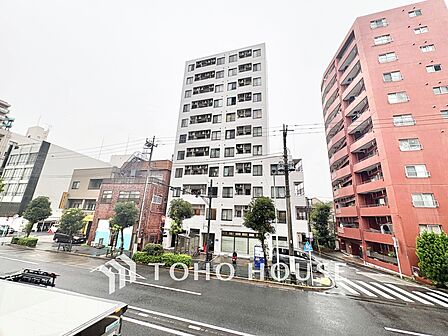 開放感のある角地にそびえるシャープなフォルム。前面道路には歩道や横断歩道が整備されており、視認性と夜間の安全性にも優れた立地です。