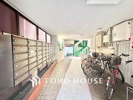 ゆったりとした幅がある1階共用通路。整然と並んだ集合ポストと整理された駐輪エリアがあり、日頃の丁寧な管理状態が窺えます。