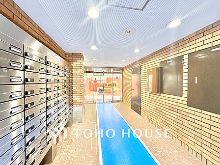 温かみのあるタイル貼りのエントランスホール。ダイヤル付きの集合ポストが整然と並び、管理体制の良さと高い防犯性が窺えます。