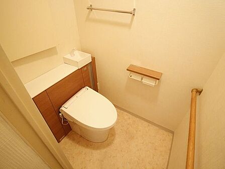 温水洗浄便座を装備したリフォーム済みトイレ。手すりや上部棚、小物を置けるスペースが確保されており、使い勝手と安全性を両立しています。お手入れがしやすく衛生的な状態を長く保てます。