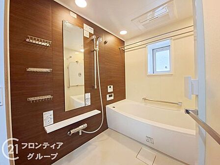 落ち着いた色調のアクセントパネルが高級感を醸し出すバスルームです。一日の疲れを優しく解きほぐす広々とした浴槽や、窓から差し込む柔らかな光が心身ともにリラックスできる至福のひとときを演出します