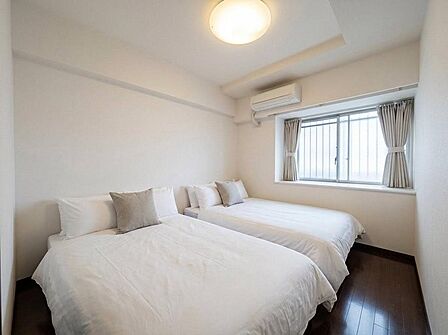 ベッドが2台置ける広々とした洋室。柔らかな自然光が差し込む快適な寝室です。(