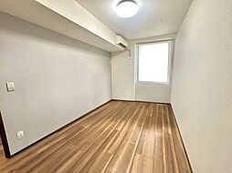 窓から光が差し込む明るい洋室。落ち着いた雰囲気で、くつろぎの時間を過ごせます。