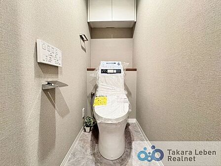 ウォシュレット機能付きのトイレは壁掛けリモコンの上位グレードを採用。便座がスッキリした印象となり、限られた空間を広く見せる効果があります。
