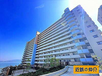 外観：水辺の景色が広がるロケーションに佇むマンション。青空の下、開放的な暮らしを叶える住まいです。