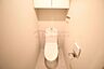 トイレ：上部吊戸棚と温水洗浄便座を備えたトイレスペース