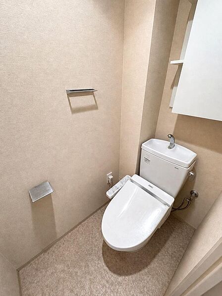 温水洗浄便座と手洗い付きタンクを備えたトイレです。上部には収納棚があり、ペーパーのストックもすっきり納まる点がご家族に嬉しいポイントです。※AIによる家具消し加工を行なっております。