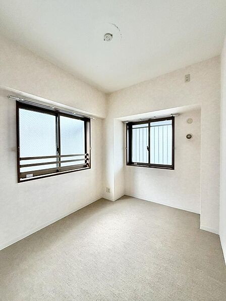 2面採光のカーペット敷き洋室。角部屋ならではの窓配置で、風通しと明るさを確保しています。足触りのやわらかい床材はお子様のいるご家庭にも向いています。