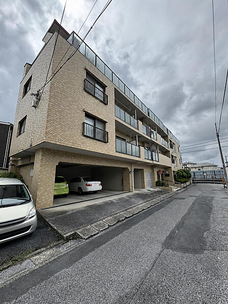 前面道路側から見た全景です。エントランス周りには植栽が配され、玄関までは手すり付きの階段でつながっています。建物脇にはゆとりのある通路が確保されています。※AIによる家具消し加工を行なっております。