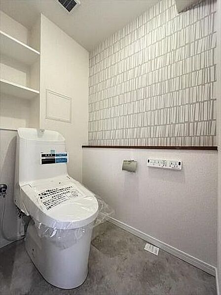 淡い色合いのアクセントクロスがおしゃれなトイレ空間。落ち着いた雰囲気で居心地の良さも魅力です。カウンターには芳香剤を置いたり小物を置くことができます。