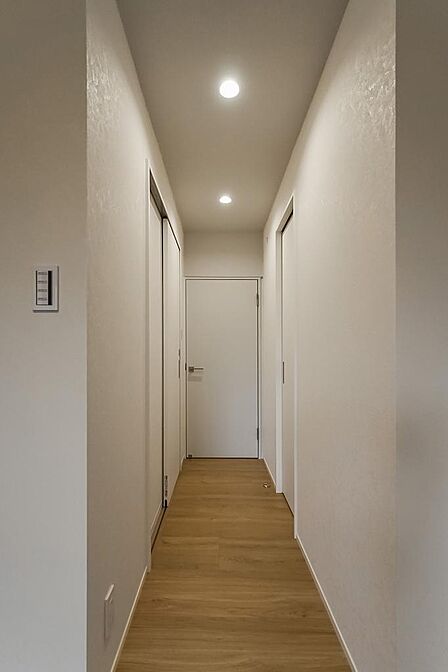 洋室から玄関へと続く廊下。向かって左側に洗面室とバスルーム、右側には大型のウォークインクローゼット(WIC)が。正面の扉の先は玄関につながります。