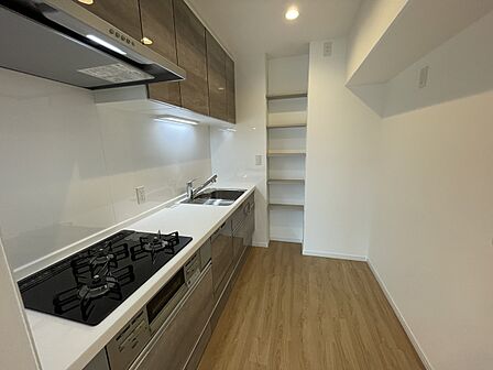 調理スペースをしっかり確保した3口コンロ付きのシステムキッチン！奥には便利な収納棚を備えており、調味料や調理器具もすっきり整理できます。毎日の料理や後片付けがはかどる機能的な設計です！
