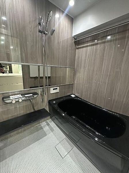 ブラックの浴槽と石目調パネルが映える、ホテルライクなバスルーム。