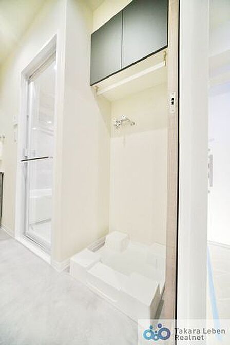 洗濯機置場。収納棚が設置されている為、洗剤類の収納場所としてお使いいただけます。