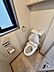 トイレ：自然換気ができる窓付きのトイレです。温水洗浄便座や手洗い、上部の収納棚など必要な設備がすっきりとまとまっています。床は落ち着いた石目調のデザインで、お手入れもしやすい空間です。