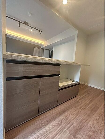 木目調の収納カウンターは、キッチン用品をすっきりと整理できます。間接照明が空間に温かみを添え、快適な食卓を演出します。