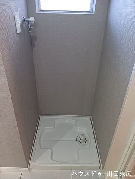 水漏れリスクを軽減する防水パンを備えた洗濯機置場。上部の小窓が空間のアクセントとなり、換気にも役立つ設計です。