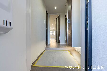 ダークブラウンの建具が落ち着きを演出する玄関アプローチ。段差を抑えた上がり框が帰宅時の安全な動線を確保。重厚感のあるドアが、住まいの第一印象を彩ります。