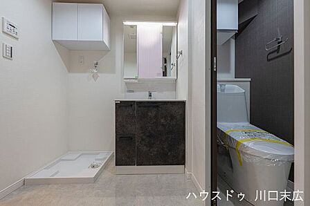 三面鏡裏収納付きの洗面化粧台と、上部に吊戸棚を備えた洗濯機置場。リネン類や洗剤を機能的に収納でき、生活感の出やすい水回りを常に整然とした状態に保つことができます。
