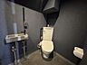 トイレ：ダークトーンの壁面がスタイリッシュなトイレ空間。温水洗浄機能付き便座に加え、壁面にはコンパクトな手洗いボウルを設置。シックなカラーリングで統一された、清潔感と洗練されたデザイン性を備えた空間です。