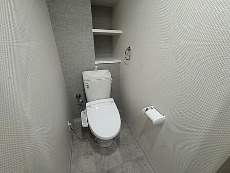 清潔感のあるホワイトを基調としたトイレ。温水洗浄便座付きで、毎日快適に使用できます。背面には棚があり、トイレットペーパーのストックやお掃除用品、芳香剤などを置いてすっきり片付けられます！