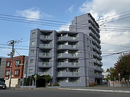 落ち着いた上品な色合いのタイル張りが印象的なマンション外観。バルコニーの立体的なデザインが建物に表情を添えています。道路側から建物全体を見渡せるため、外観と周辺の雰囲気を併せて確認いただける一枚です。