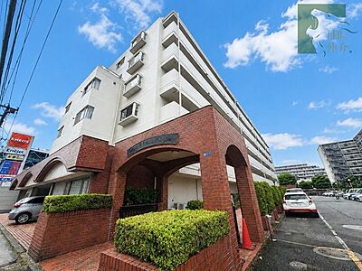 外観：青空に映える白の外壁と落ち着いた赤茶色のレンガ調デザインが調和した、風格を感じさせる佇まいです 