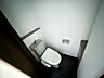 トイレ：温水洗浄便座を備えたトイレです。上部に収納棚が設けられています。
