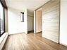 洋室：大きな窓から光を取り込む、明るい印象の洋室。木目調の床と建具がやさしい雰囲気を演出し、ハンガーパイプ付きの収納スペースも備えています。