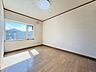 室内：大きな窓から山並みを望む洋室約6帖。陽当たり・風通しとも良好な空間です。