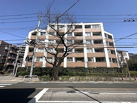 落ち着いた街並みに溶け込む、ベージュ×ホワイトの外観。マンション周辺の道路は歩道が整備されています。【外観】