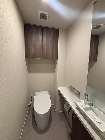 温水洗浄便座付きのトイレです。手洗いカウンターや鏡・吊り戸棚が備わった、使い勝手の良い仕様です。【トイレ】