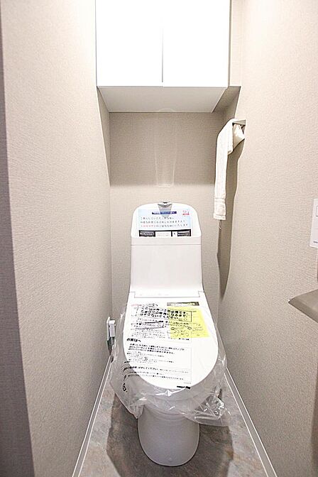 清潔感のあふれるトイレ空間。トイレットペーパーなどを隠せる便利な上部吊戸棚付き