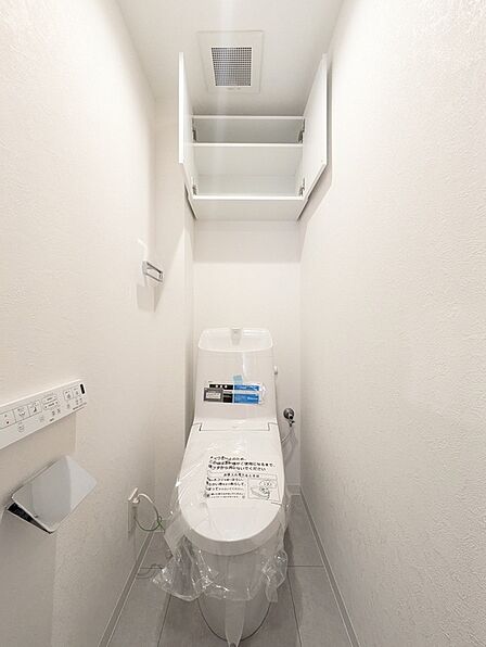 温水洗浄便座を備えた清潔感のあるトイレ。上部には収納棚があり、消耗品などもすっきり収納できます。