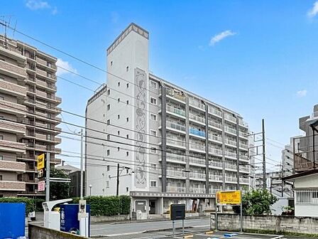 白を基調とした外観が印象的なマンションです。周囲には高い建物が並び街並みに調和しています。道路に面した立地で車でもアクセスしやすいです。
